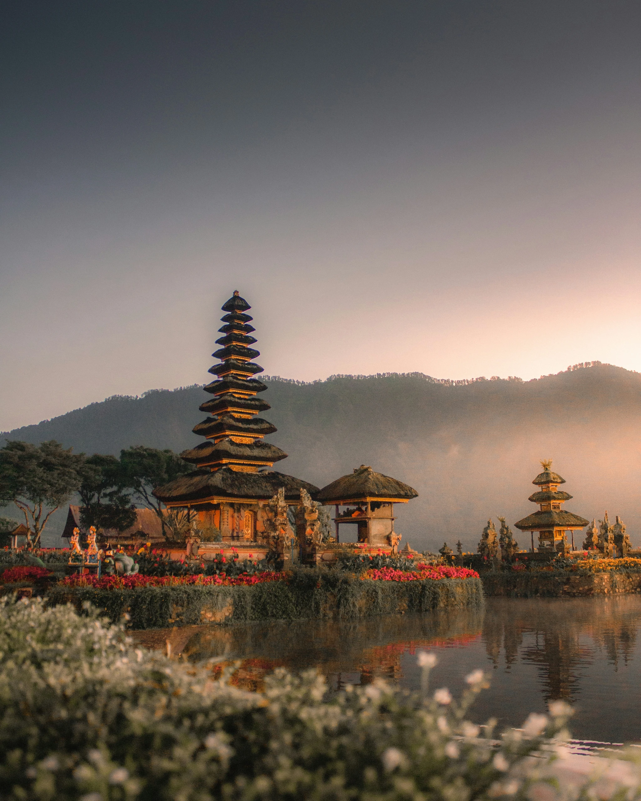 Pura Ulun Danu Beratan, the tiered lake temple in Tabanan, Bali, at dawn with mist rising over the mountains